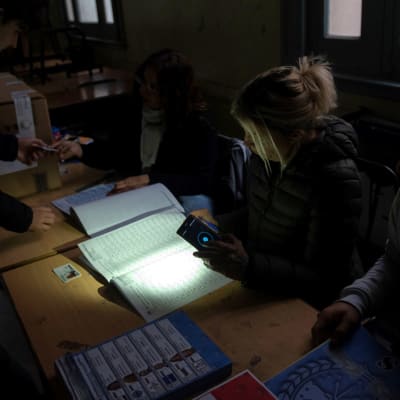 En valfunktionär använde sin mobiltelefon för att lysa upp sina papper i en vallokal i Rosario. Trots strömavbrottet genomfördes regionalval i delar av Argentina på söndagen. 