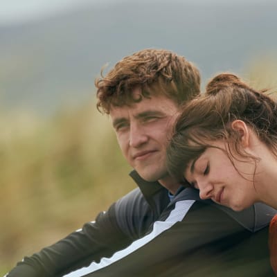 Sarjan Connell (Paul Mescal) ja Marianne (Daisy Edgar-Jones) istuvat vierekkäin heinikossa. Marianne nojaa Connellin olkapäähän.