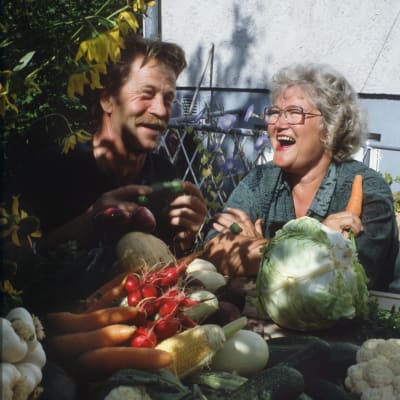 Puutarhuri Arno Kasvi ja Tarja Flemming nauravat edessään kasa erilaisia vihanneksia.