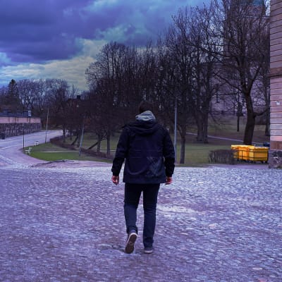 Mies kävelee Suomenlinnassa selkä kameraan päin