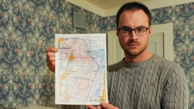 Philip Mannfolk håller upp en karta över Närpes