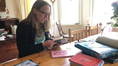 Anna Dahlbacka bläddrar i böcker vid bordet. 