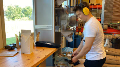 En ung man packar kaffebönor i påsar med hjälp av en packningsmaskin.