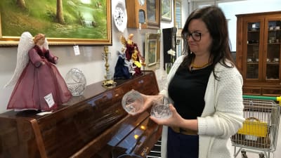 Lotta Palander undersöker glaskoppar på loppmarknad