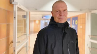 En man i svart jacka står i en korridor. 