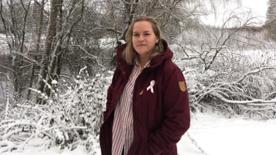 josefin ahslog bär en vinröd vinterjacka i ett snörikt landskap. hon ler. 