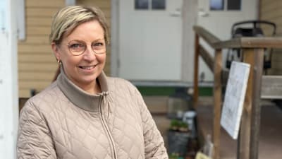 Kvinna vid ett gult trähus i Korpo.