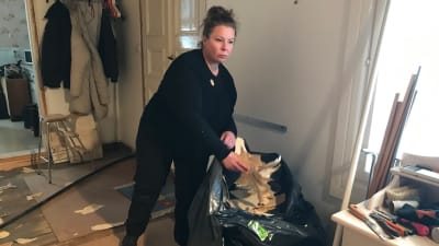 Annika Rosenström plockar in skräp i en svart sopsäck