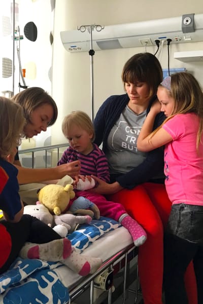 en treårig flicka på sjukhussängen tillsammans med sina syskon, mamma och läkare