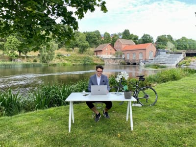 En man som sitter vid ett skrivbord på en gräsmatta i Billnäs bruk. 