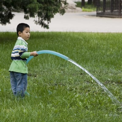 En kinesisk pojke leker med en vattenslang i Peking i Kina den 15 april 2007. Peking, liksom många andra städer i Kina står inför en grundvattenskris.