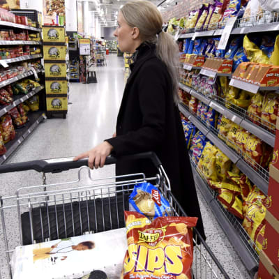 Kvinna med shoppingvagn i supermarket.