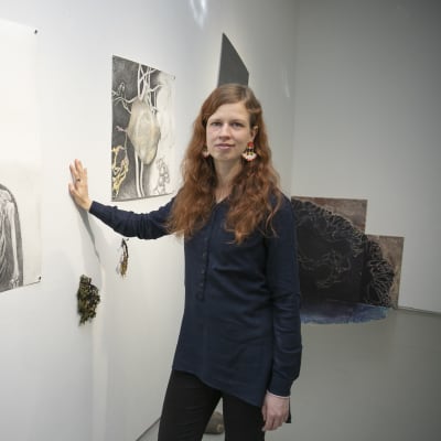 Nainen seisoo taidenäyttelyssä teoksen edessä.