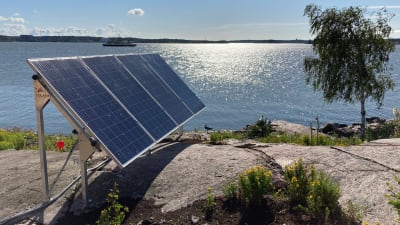 Solpaneler på en klippa vid havet.