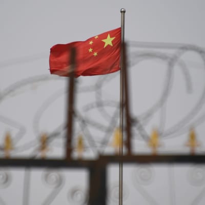 Taggtråd i förgrunden och Kinas flagga i bakgrunden.