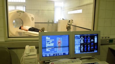 Kvinna ligger i skiktröntgen-apparat, datortomografi