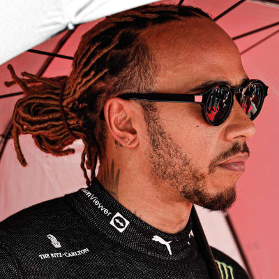 Lewis Hamilton står under ett paraply.