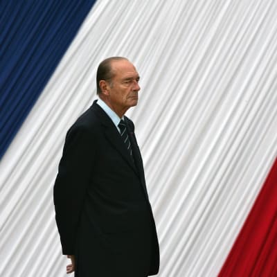 Jacues Chirac framför en stor fransk flagga.