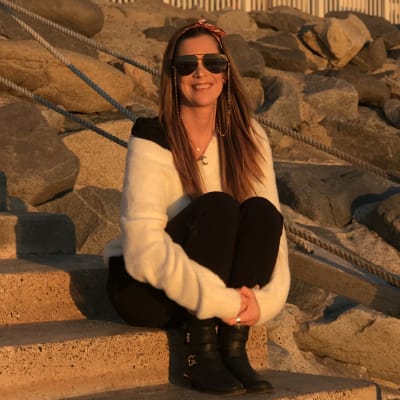 Emilia Lintuluoto-Waisanen sitter på en trappa och tittar in i kameran.