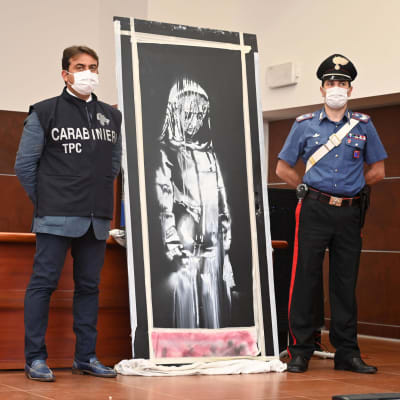 Kaksi poliisia esittelee Banksyn teosta.
