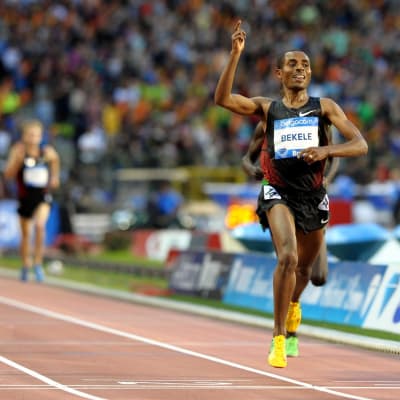Etiopisk distanslöpare löper i mål och höjer handen i en segergest.