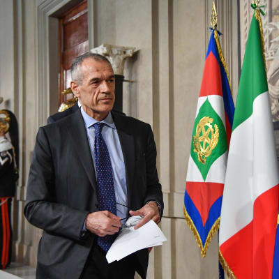Carlo Cottarelli vid den italienska och EU-flaggan. 