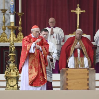 Kardinal Giovanni Battista Re stänker vigvatten över påve emeritus Benedictus XVI:s kista under begravningsmässan på Petersplatsen. Påve Franciskus ser på i bakgrunden.