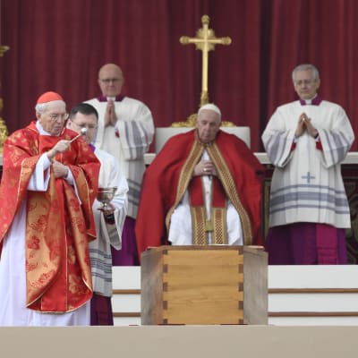 Kardinal Giovanni Battista Re stänker vigvatten över påve emeritus Benedictus XVI:s kista under begravningsmässan på Petersplatsen. Påve Franciskus ser på i bakgrunden.