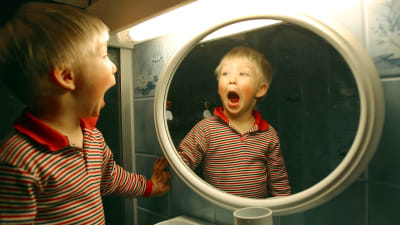 En pojke ser sig själv i spegeln