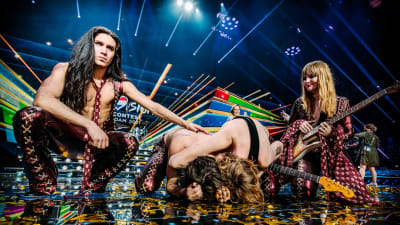 Ett band beståendes av fyra personer som står på en scen efter att ha vunnit Eurovision Song Contest. Två av dem ser ner i golvet.