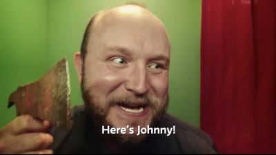Mies lähikuvassa kuvauskopissa kirves kädessä, kuvassa tekstitys "Here's Johnny!"