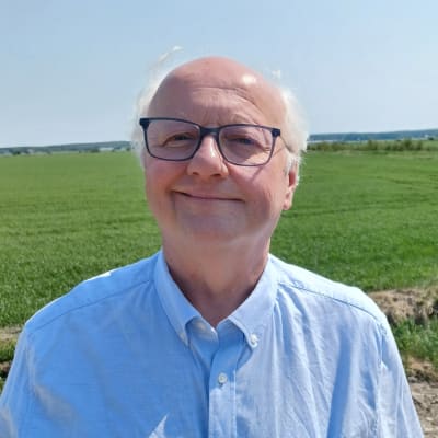 Professor i geologi Olav Eklund leende framför ett fält