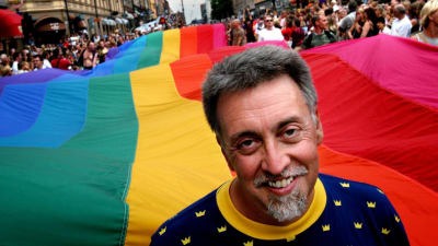 Gilbert Baker står framför en 250 meter lång regnbågsflagga på Prideparaden i Stockholm år 2003.