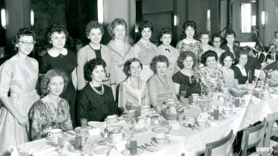 Svartvit bild på kvinnor vid middagsbord.