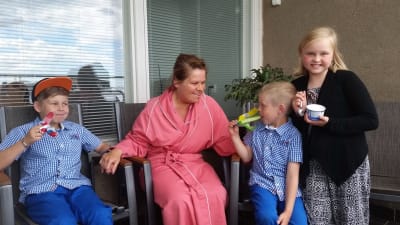 Nina Brännkärr-Friberg i sjukhuskläder tillsammans med barnen.
