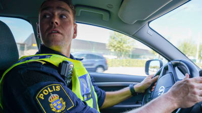 Polisinspektör Jonas Berg tittar över axeln då han kör bil.