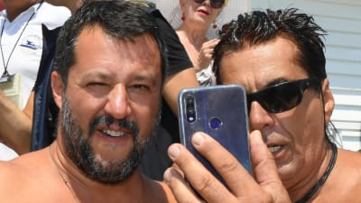 Inrikesminister Matteo Salvini tar en selfie med en anhängare på en strand i Taormina, Sicilien. Båda har bar överkropp.