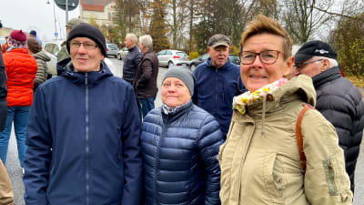 Personer står på en trottoar.