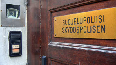 Skylt på skyddspolisens dörr där det står: Suojelupoliisi - skyddspolisen.