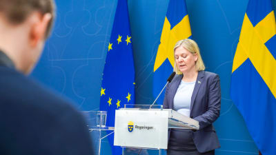 Magdalena Andersson håller tal framför Sveriges flagga.