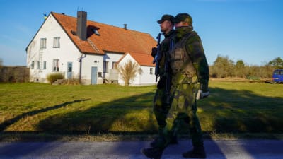 Svenska militärer går framför en vit lada på Gotland.