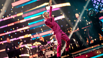 Antti Tuisku esiintyy värikäs puku yllään SuomiLOVE-lavalla. 