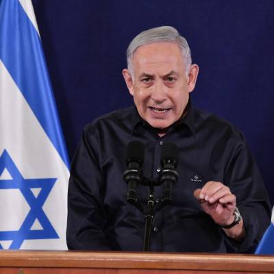 Benjamin Netanyahu talar mellan två israeliska flaggor.