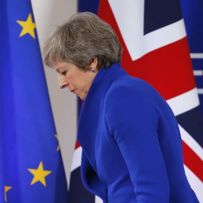 Storbritanniens premiärminister Theresa May framför en EU:s och Storbritanniens flaggor