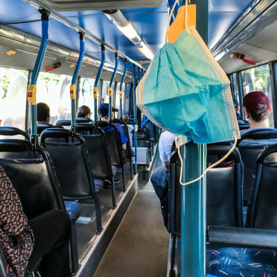 Hengityssuojain roikkuu bussissa.