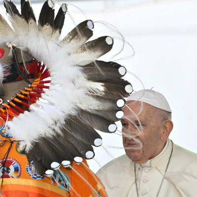 Påve Franciskus möter en person från urbefolkningen med fjäderhuvudbonad.