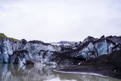 Glaciären Solheimajökull med en stor sjö av smältvatten framför sig.