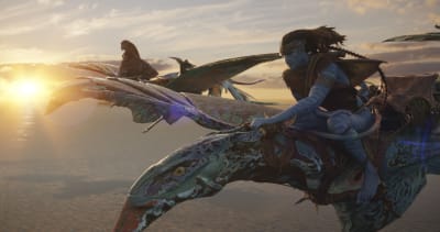 Två blå avatarer flyger på varsin drake i solnedgången.
