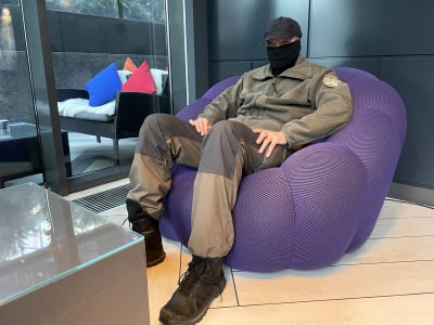 En finländsk officer sitter i en hotellobby i Kiev med keps på huvudet och största delen av ansiktet täckt av tyg.
