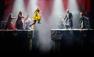 En ung kvinna i gul klänning som hoppar över en klyfta.